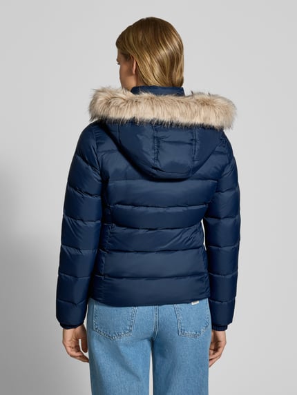 Frauenmodel trägt Regular Fit Daunenjacke mit Kunstfell von Tommy Jeans in Dunkelblau, gesteppt, glatte Struktur, Ganzkörperansicht Rückansicht. Damen Daunenjacke von Tommy Jeans