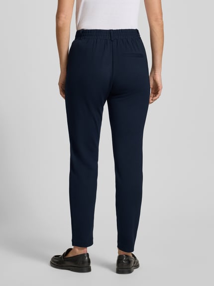 Vrouwenmodel draagt Easy Pants met Bundfalten van TOM TAILOR, donkerblauw, smal toelopende pijpen, elastische tailleband, rugaanzicht.