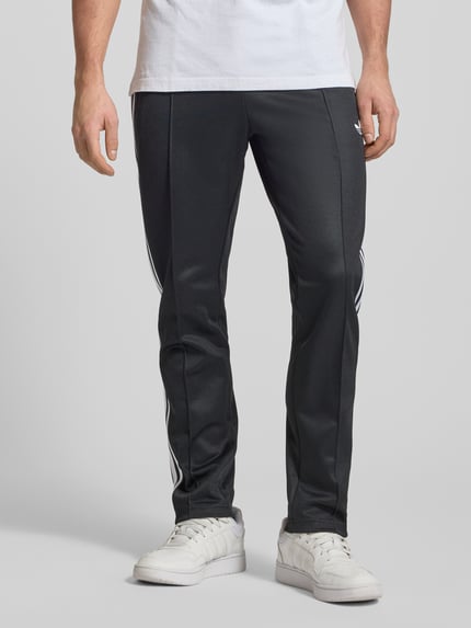 Męski model nosi Sweatpants mit elastischem Bund od adidas Originals, luźny krój, czarny kolor, bawełniana mieszanka, widok z przodu, zbliżenie na nogi.
