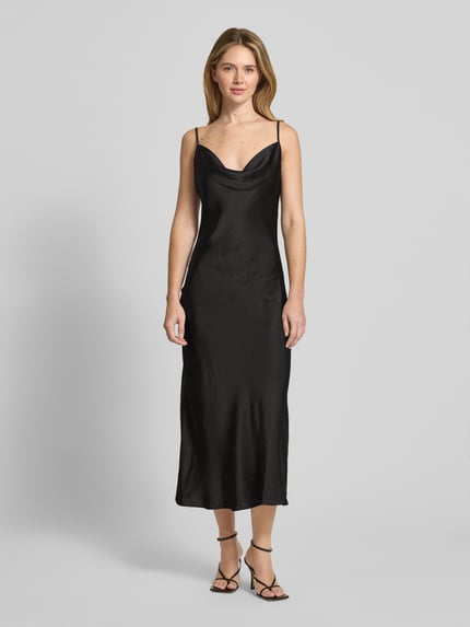 Frauenmodel trägt Midikleid mit Ziersteinbesatz Modell 'NEW AKILINA' von Guess aus schwarzem Satin mit Crinkle-Optik, körpernaher Passform, verstellbaren Spaghettiträgern, Wasserfall-Ausschnitt und Midilänge, Ganzkörperansicht von vorne.
