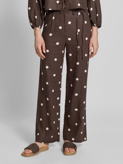 Frauenmodel trägt Stoffhose mit Schleifen-Detail von Jake*s Casual in Dunkelbraun mit weißen Punkten, Lockerer-Schnitt, Nahaufnahme Unterkörper. Bundweite bei Größe 36: 40 cm, Innenbeinlänge bei Größe 36: 83 cm.