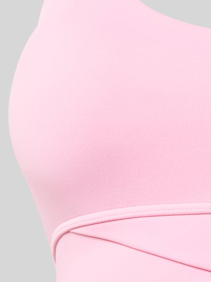 Frauenmodel trägt Sport-BH mit Neckholder Modell 'ACTIVE' von P.E Nation in Rosa, glatte Textur, Detailaufnahme Oberkörper.