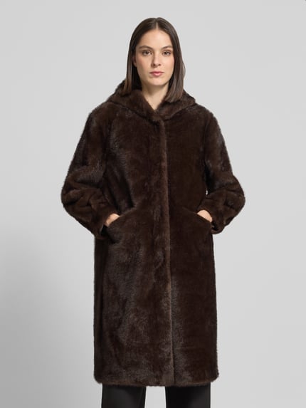 Kobieta nosi Mantel mit Kapuze und Eingrifftaschen od Rinascimento, brązowy sztuczny futerko, krój prosty, kryte zapięcie, boczne kieszenie, długość tyłu w rozmiarze S: 101 cm, zdjęcie całej sylwetki z przodu.