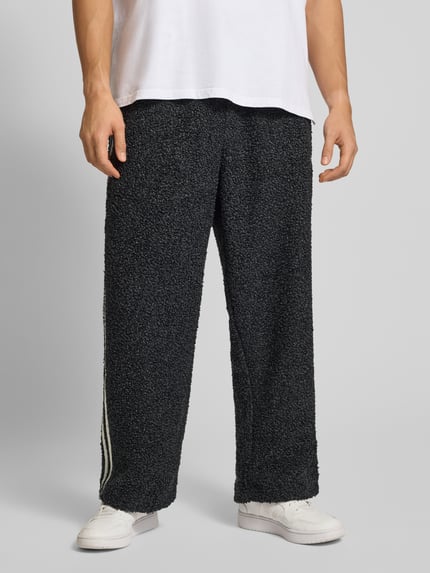 Männermodel draagt Sweatpants met elastische tailleband van adidas Originals, bouclé-look, los model, donkergrijs, volledige voorkant.