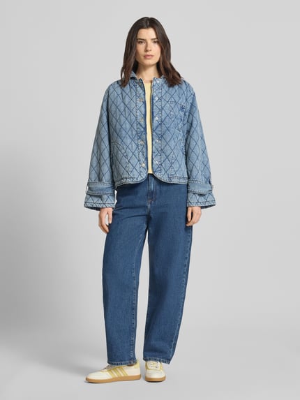 Frauenmodel trägt Jacke mit Steppnähten Modell 'Viola' von LOLLYS LAUNDRY aus Baumwoll-Mix in Denim-Optik, Relaxed-Fit, Umlegekragen, Knopfleiste, Eingrifftaschen, mittleres Blau, strukturierte Oberfläche, Ganzkörperansicht von vorne.