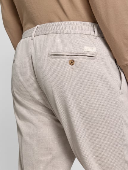 Männermodel trägt Regular Fit Anzughose aus Viskose-Mix Modell 'Lester' von JOOP! Collection, Gesäßtaschen, Nahaufnahme Rückansicht. Bundweite bei Größe 50: 44 cm, Innenbeinlänge bei Größe 50: 76 cm, leichte Struktur, Stretch-Anteil.