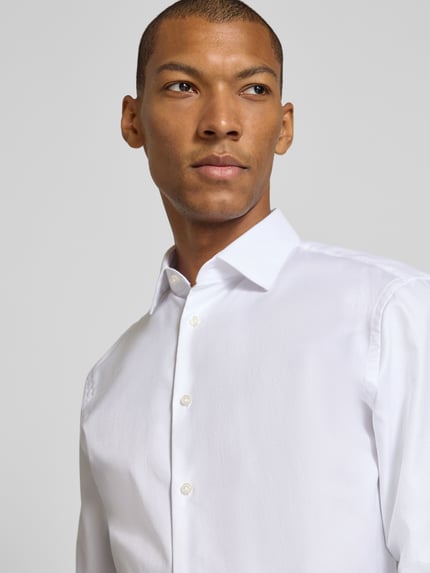 Männermodel trägt weißes Slim Fit Businesshemd mit extra langem Arm von Jake*s, glatte Oberfläche, Nahaufnahme Oberkörper.