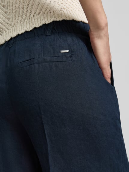 Frauenmodel trägt Leinenshorts mit Eingrifftaschen von Christian Berg Woman, dunkles Reines Leinen, Regular-Fit, Detailaufnahme Rückansicht.