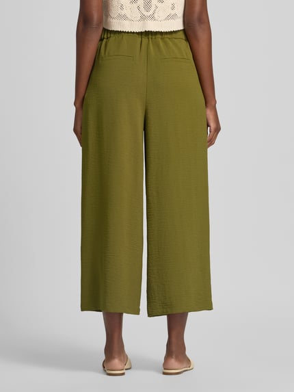 Frauenmodel trägt Wide Fit Culottes mit Strukturmuster von zero in Olive, verkürzte Passform, Bundfalten, Ganzkörperansicht Rückansicht
