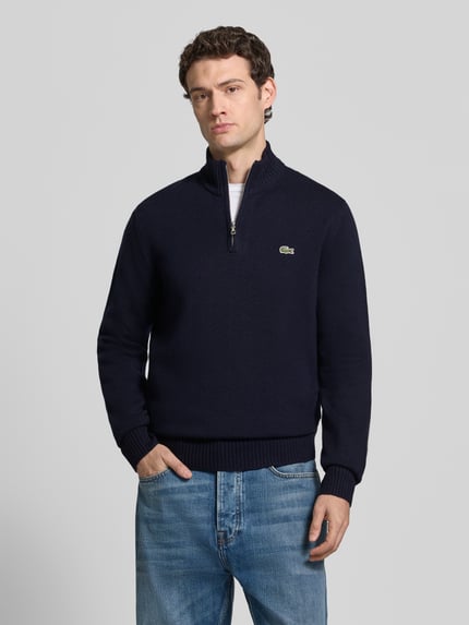 Männermodel trägt Pullover mit Logo-Patch Troyer von LACOSTE in dunkelblauer Strickoptik, Struktur, Regular Fit, hochgeschlossen, Ganzkörperansicht von vorne
