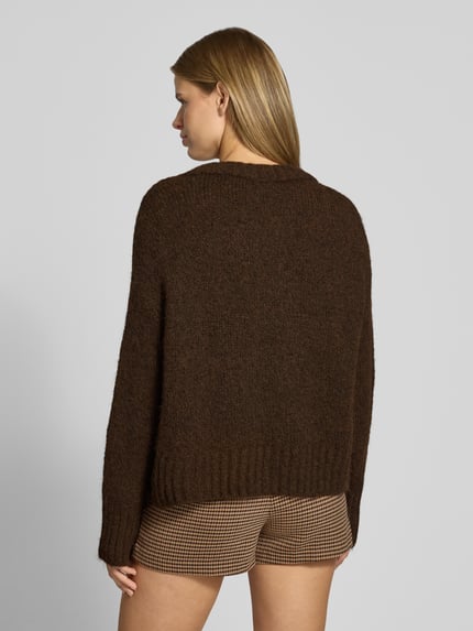 Frauenmodel trägt Pullover mit tiefem V-Ausschnitt von ONLY in Dunkelbraun, grobe Strickstruktur, Ganzkörperansicht Rückansicht, Damen Pullover von ONLY.