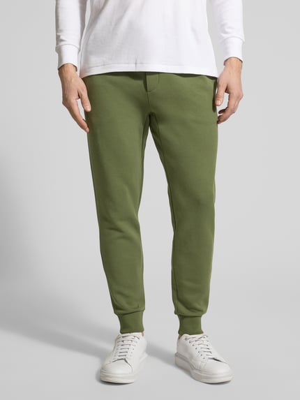 Männermodel trägt Tapered Sweatshorts aus Baumwoll-Mix von Polo Ralph Lauren, Optik: Unifarben, Passform: Tapered, Logo-Stitching, Tunnelzug, Bundabschluss elastisch, seitliche Eingrifftaschen, Gesäßtasche, Materialverarbeitung: Sweat, Material: Baumwoll-Mix, Ganzkörperansicht von vorne.