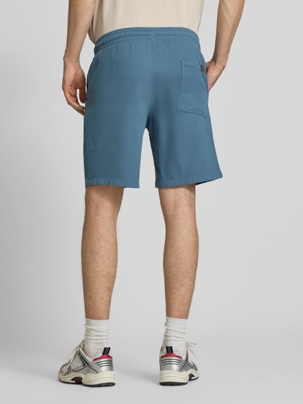 Männermodel draagt Shorts met structuurpatroon model 'JAIDEN' van Jack & Jones, puur katoen, regular fit, elastische band met tunnelkoord, bandwijdte maat M 43 cm, binnenbeenlengte maat M 23 cm, blauwe tint, rechte vormen, gladde textuur, ganzkörperansicht rückansicht.