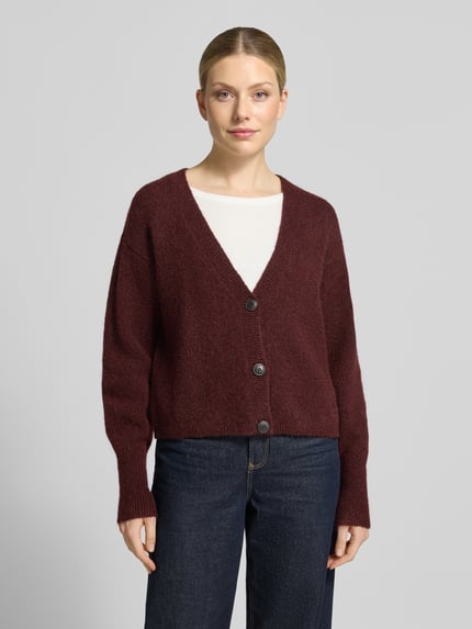 Frauenmodel trägt Cardigan aus Wolle mit Logo-Stitching Modell 'Sirala' von HUGO in Dunkelrot, strukturierte Strickoptik, Knopfleiste, gerippte Abschlüsse, unifarben, Cropped Länge, V-Ausschnitt, Ganzkörperansicht von vorne.