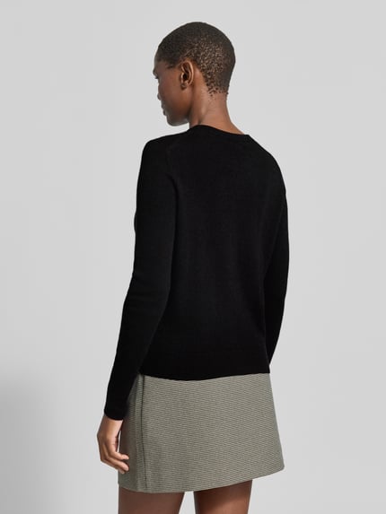Frauenmodel trägt Strickjacke aus reinem Kaschmir mit durchgängiger Knopfleiste von Christian Berg Woman, schwarze Farbe, Regular Fit, gerippte Abschlüsse, Rückenansicht, Nahaufnahme Oberkörper.