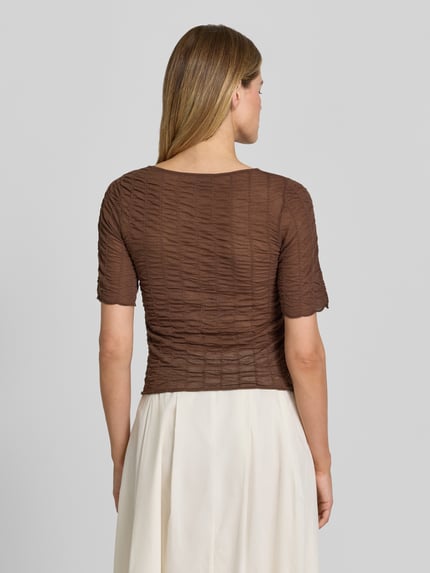 Modelka kobieca nosi Strickshirt aus Viskose-Mix mit Rundhalsausschnitt od Christian Berg Woman Selection, brązowy kolor, krój slim fit, wzór strukturalny, długość tyłu w rozmiarze S: 82 cm, długość rękawa w rozmiarze S: 29 cm, widok całej sylwetki z tyłu.