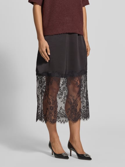 Frauenmodel trägt Regular Fit Midi-Rock mit Spitzenbesatz Modell 'OLLIE' von VERO MODA, schwarze Farbe, Textur-Mix, Nahaufnahme Unterkörper. Damen Midi-Rock von VERO MODA