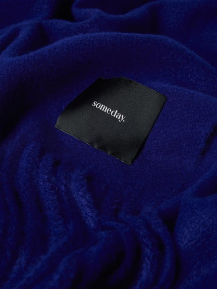 Produktfoto, Schal mit Ausfransungen Modell 'Barula' von Someday, rechteckige Form, intensiv blau, feine Textur, Label-Detail sichtbar.