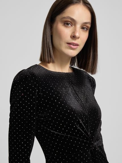 Frauenmodel trägt Cocktailkleid im Allover-Look Modell 'HELLA' von YAS, Rundhalsausschnitt, figurbetont, schwarzer Stoff mit feiner Punktstruktur, Nahaufnahme Oberkörper.