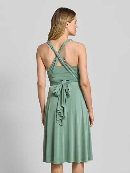 Frauenmodel trägt Knielanges Cocktailkleid mit tiefem V-Ausschnitt von Rose Avenue in Mintgrün, Taillierter Schnitt, Taillenband, Rückseite, Ganzkörperansicht Rückansicht.