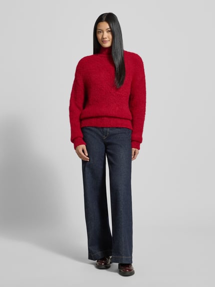 Frauenmodel trägt Strickpullover mit Stehkragen und überschnittenen Schultern von Milano Italy in Rot, Material-Mix mit Mohair, Ganzkörperansicht von vorne.