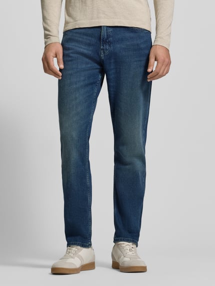 Männermodel trägt Slim Fit Jeans aus Baumwoll-Mix Modell 'SMU ONYX' von BOSS Orange in Denim-Optik, 5-Pocket, Ganzkörperansicht von vorne.