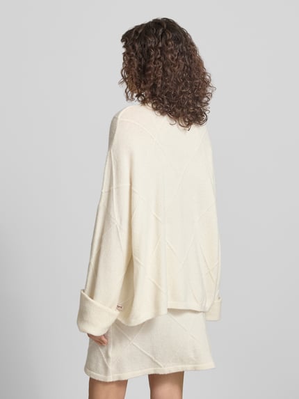 Frauenmodel trägt Regular Fit Pullover mit Alpaka-Anteil Modell 'Liora' von OH APRIL, cremefarbener Strick, extralange Ärmel, Rückansicht, Ganzkörperansicht.