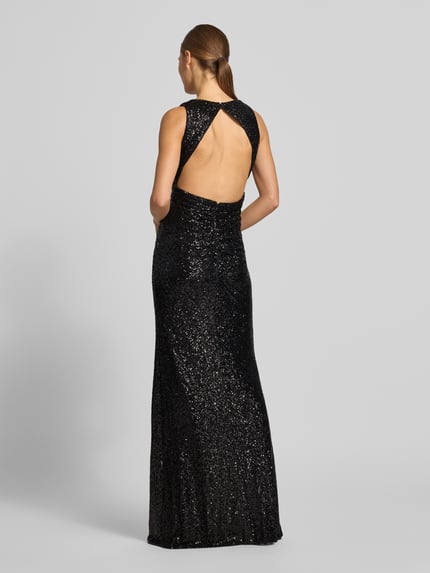 Modelka nosi Abendkleid mit Pailletten-Cut-Out von JAKE*S COCKTAIL, czarny połyskujący satynowy materiał, cekiny, maxi, bez rękawów, wycięcie na plecach, widok całej sylwetki z tyłu.
