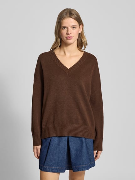 Frauenmodel trägt Regular Fit Strickpullover mit Woll-Anteil Modell 'MARI' von Only in brauner Melange-Optik, V-Ausschnitt, Ganzkörperansicht von vorne.