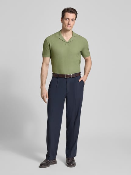Męski model nosi Regular Fit Poloshirt mit Reverskragen und V-Ausschnitt von Armani Exchange, bawełna, krój regular fit, długość tyłu w rozmiarze M: 66 cm, kolor jasna zieleń i granat, cała sylwetka z przodu.