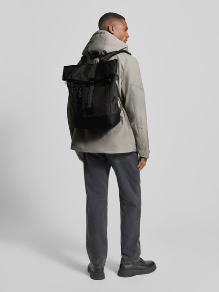 Männermodel trägt Rucksack im Roll Top Design Modell 'EDDIE' von Strellson, Optik: Unifarben, Struktur, Label Patch, recyceltes Material, Hauptfach, Laptopfach, Rucksackgurte, Verschluss: Roll Top, Reißverschluss, Schnalle, Ganzkörperansicht Rückansicht.