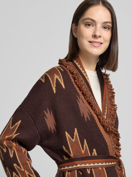 Frauenmodel trägt Relaxed Fit Strickjacke aus Woll-Mix mit Fransen von Stefanel, braun gemustert, weiche Textur, Nahaufnahme Oberkörper.