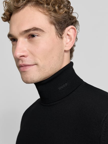 Männermodel trägt Turtleneck aus Wolle mit Feinstrickstruktur von HUGO in Schwarz, unifarben, Nahaufnahme Oberkörper.
