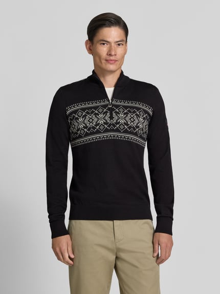 Männermodel trägt Wollpullover mit Label-Patch Modell 'Liaset' von Dale of Norway, schwarz mit grauem Muster, Nahaufnahme Oberkörper. Reine Wolle, gerader Schnitt, Troyer-Kragen, Rückenlänge 66 cm, Ärmellänge 69 cm.