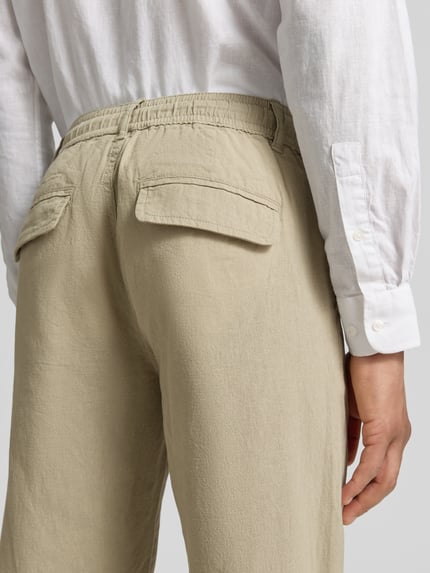 Männermodel trägt Hose aus Leinen-Baumwoll-Mix mit elastischem Bund von Lindbergh, regular fit, steekzakken, band, mix van linnen en katoen, bandwijdte maat M 40 cm, binnenbeenlengte maat M 79 cm, detailaufnahme rückansicht.