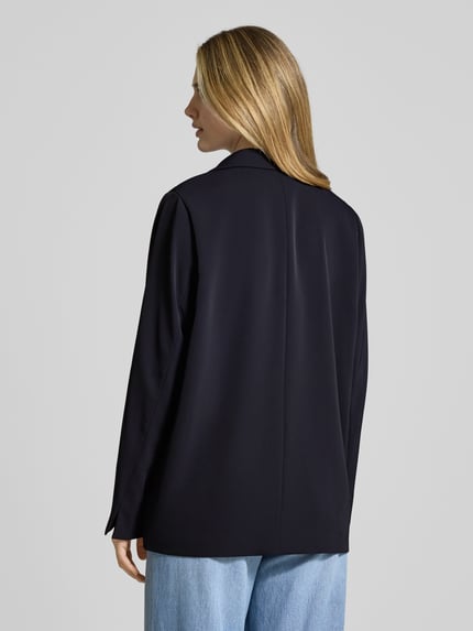 Frauenmodel trägt Relaxed Fit Blazer mit Reverskragen von Comma, Elastischer-Material-Mix, dunkelblau, Rückansicht, Ganzkörperansicht Rückansicht. Rückenlänge bei Größe 36: 70 cm, Brustweite 49 cm, Ärmellänge 63 cm, Knopfverschluss, Paspeltaschen.