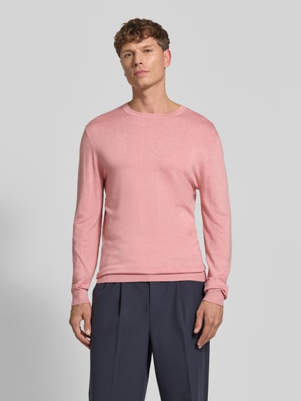 Männermodel trägt Strickpullover mit geripptem Rundhalsausschnitt von MCNEAL in Rosa, schlichte Struktur, Ganzkörperansicht von vorne, taillierte Passform, leicht überschnittene Schultern, gerippte Abschlüsse, Rückenlänge 70 cm, Ärmellänge 65 cm.