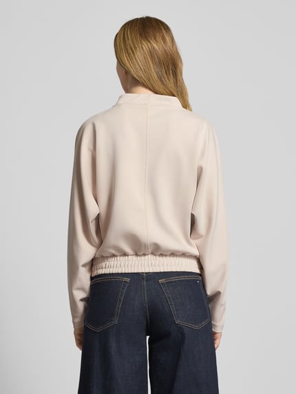 Frauenmodel trägt Sweatshirt mit geripptem Stehkragen Modell 'Gulitta' von Opus in Beige, Modal-Mix mit Stretch-Anteil, lockerer Schnitt, elastischer Bund, Ganzkörperansicht Rückansicht.