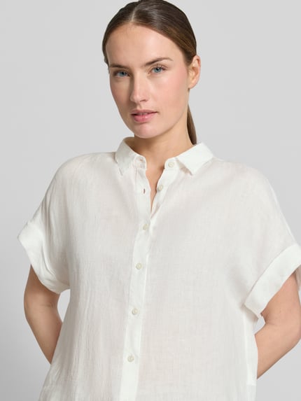 Frauenmodel trägt Leinenbluse mit Knopfleiste Modell 'DOLLY' von 0039 Italy in Weiß, reine Leinen-Qualität, Regular-Fit, Hemdblusenkragen, Ärmel mit Aufschlag, Rückenlänge 64 cm bei Größe S, Nahaufnahme Oberkörper.