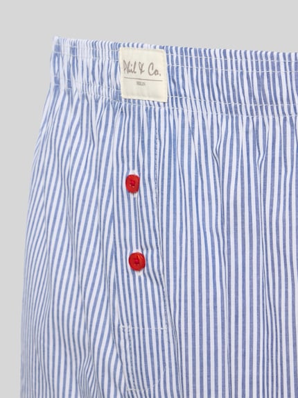 Produktfoto, Boxershorts im 6er-Pack mit Label-Patch von Phil&Co., blau-weiß gestreift, rote Knöpfe, Baumwolle, elastischer Bund, Detailaufnahme