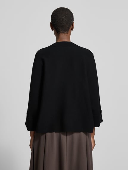 Vrouwenmodel draagt Relaxed fit gebreide pullover uit viscosemix Model 'OKTOBER' van comma, zwart met ribboorden, ruglengte maat S 55 cm, mouwlengte maat S 38 cm, dames strickpullover, rugaanzicht.