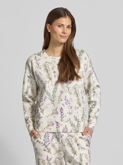 Kobiece modelka nosi bluzę Sweatshirt O-Neck mit Lavendelprint od Christian Berg Woman z mieszanki wiskozy i elastanu, luźny krój, dekolt okrągły, elastyczne wykończenia, nadruk w lawendę, jasne kolory, całkowity widok z przodu