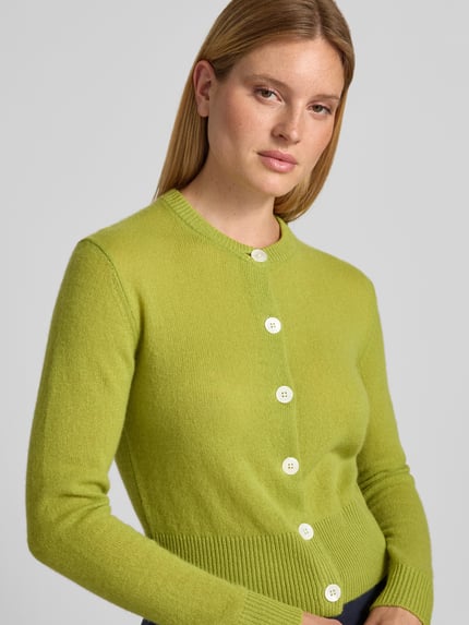 Frauenmodel trägt Strickjacke aus Kaschmir mit Rundhalsausschnitt Modell 'Karina' von JOOP! in Slim Fit, leuchtend grün, Nahaufnahme Oberkörper. Reiner Kaschmir, Knopfleiste, feine Textur, Rückenlänge 54 cm, Ärmellänge 70 cm.