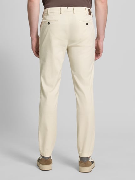 Männermodel trägt Slim Fit Hose mit Eingrifftaschen Modell 'Tybalt 5' von g1920 aus Baumwoll-Lyocell-Mix in Beige, Ganzkörperansicht Rückansicht.