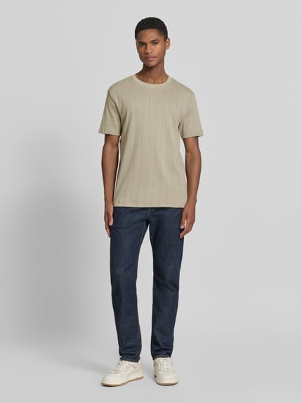 Männermodel trägt T-Shirt in Jaquard-Strick mit Rundhalsausschnitt von Lindbergh, Reine Baumwolle, Regular-Fit, Label-Detail, Beige, Ganzkörperansicht von vorne.