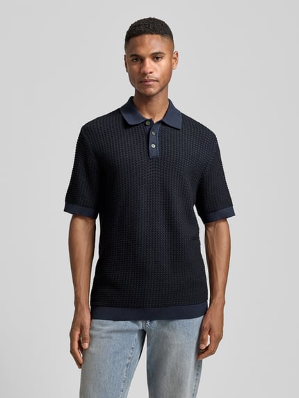 Męski model nosi Regular Fit Poloshirt in Strick-Optik Modell 'Kingsley' von Jack & Jones Premium z bawełny, krój regular fit, kołnierzyk polo, krótki rękaw, elastyczne wykończenia, imitacja dzianiny, długość tyłu w rozmiarze M: 77 cm, widok całej sylwetki z przodu.