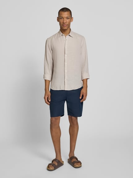 Männermodel trägt Regular Fit Freizeithemd aus reinem Leinen Modell 'REGKYLIAN' von SELECTED HOMME in Beige, unifarben, Ganzkörperansicht von vorne.