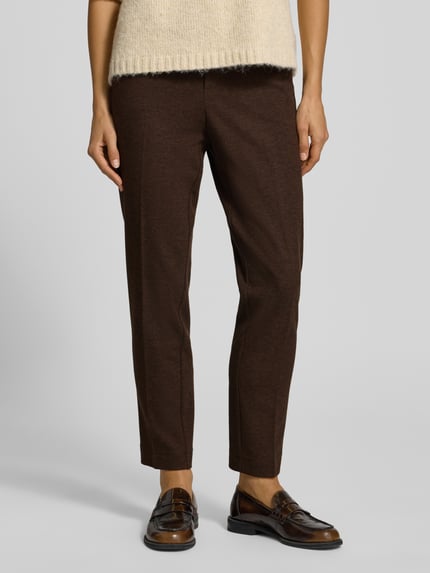 Frauenmodel trägt Regular Fit Hose mit Bügelfalte von Stehmann, dunkelbraun, Strukturmuster, Webware, seitliche Eingrifftaschen, Ganzkörperansicht von vorne.