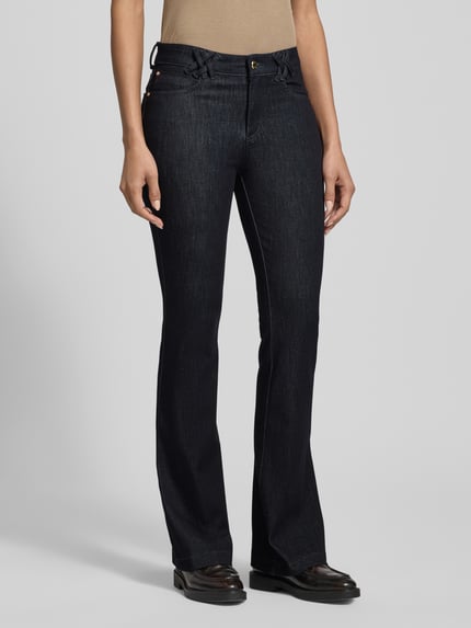 Frauenmodel trägt Flared Fit Jeans im 5-Pocket-Design Modell 'Shakira' von BRAX aus elastischem Baumwoll-Mix, dunkle Farbe, Ganzkörperansicht von vorne.