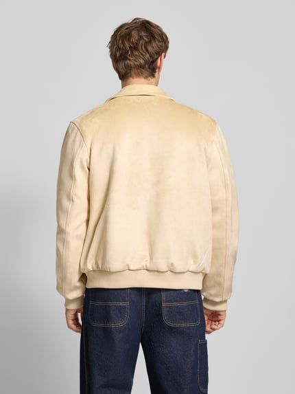 Männermodel trägt Jacke in Leder-Optik mit Label-Stitching von KARL KANI, Material-Mix mit Stretch-Anteil, Regular Fit, Ganzkörperansicht Rückansicht.
